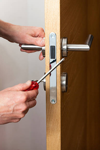 Hands repairing a door lock with a screwdriver تركيب شواحن السيارات في أبوظبي