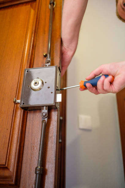 Man changing a lock on the house door تركيب شواحن السيارات في أبوظبي