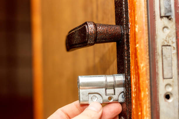 Locksmith installs new door lock into wooden door