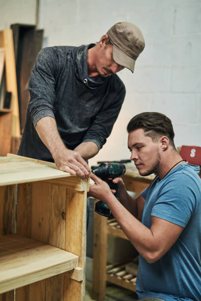 Cropped shot of two carpenters putting together a wood piece in a workshop تركيب شواحن السيارات في أبوظبي
